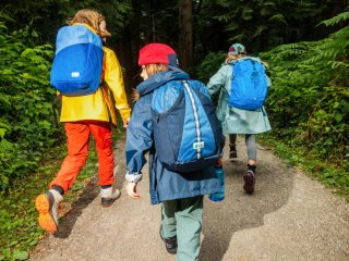 Kids wearing mec backpacks walking on a road