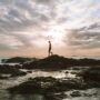 Angel Collinson walking on a rocky beach at sunset