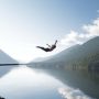 Woman diving off cliff into lake in the Coast Mountains BC